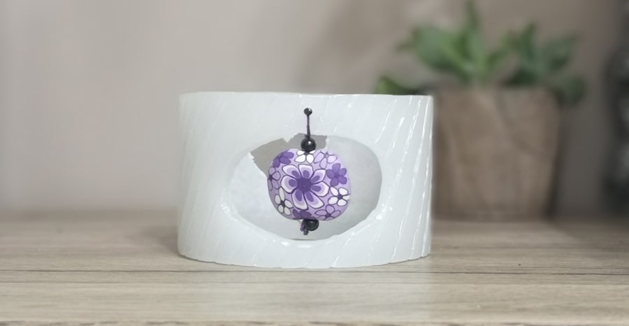 Small, wax lantern decorated with a large purple Fimo bead.