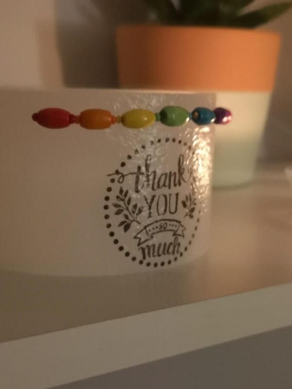 Small lantern decorated with coloured wooden beads and 'thank you' print on it.