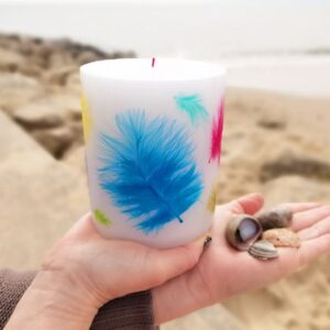 Pillar candle with coloured feathers.