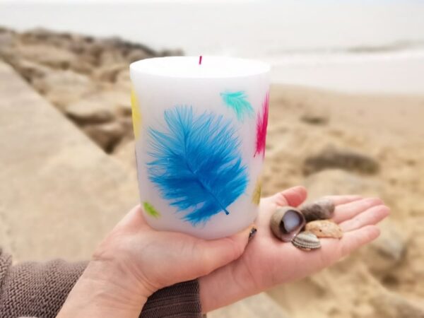 Pillar candle with coloured feathers.