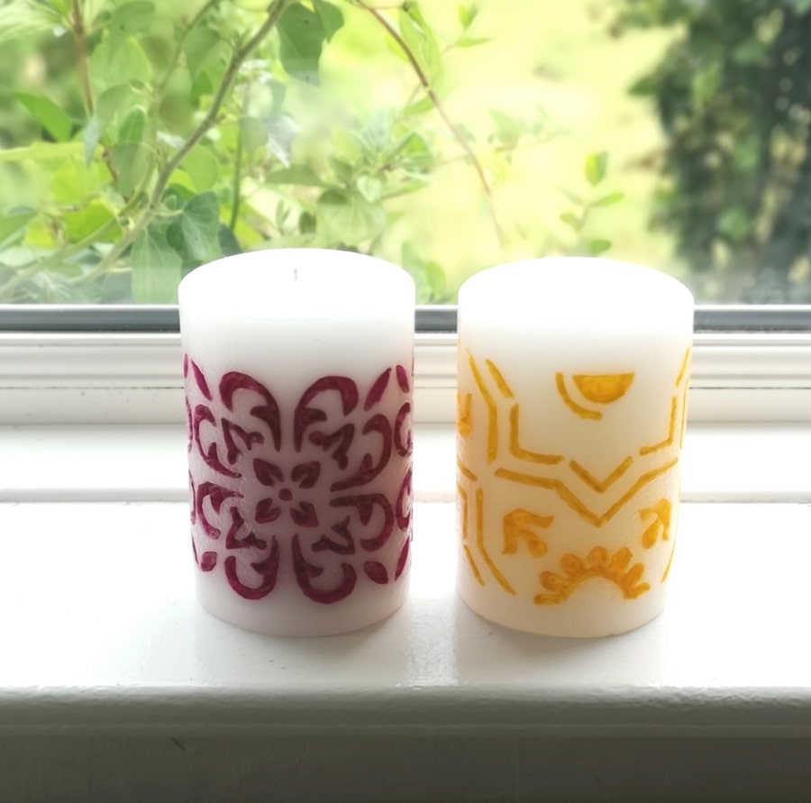 Two medium pillar candles - hand carved and hand painted with purple and yellow wax