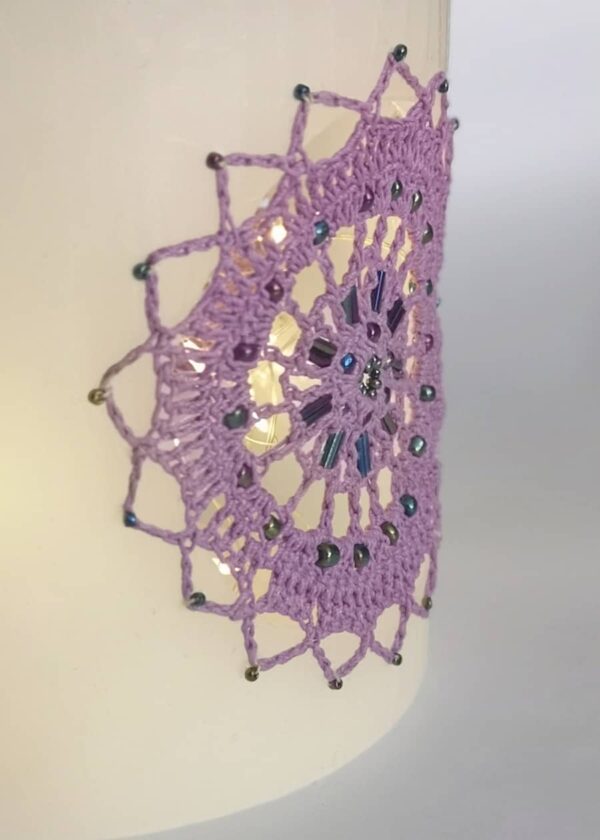 Wax lantern with violet crochet doilies, decorated with beads.