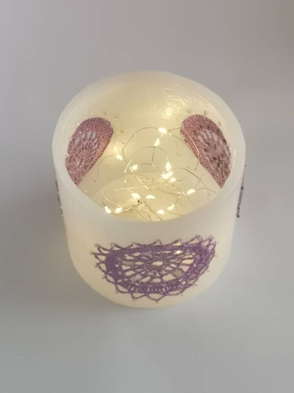 Wax lantern with violet crochet doilies, decorated with beads.