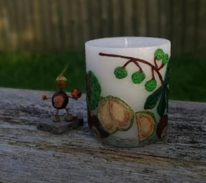 Large pillar candle with felt conkers and acorns.