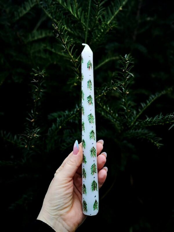 Festive taper candle with Christmas tree pattern.